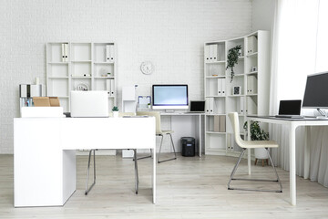 Interior of light office with modern workplaces and shelf units