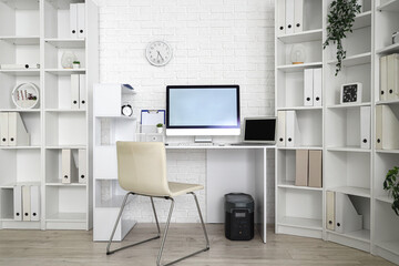 Interior of light office with modern workplace and shelf units