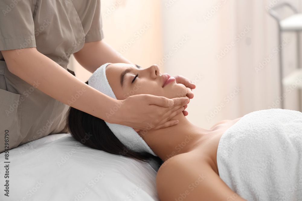 Wall mural Beautiful woman getting facial massage in salon, closeup