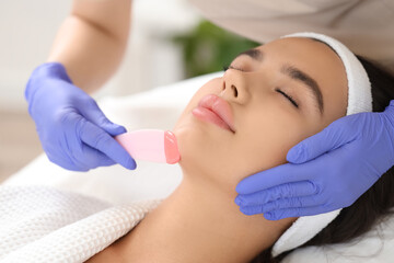 Beautician with wax removing woman's hair on chin in salon, closeup