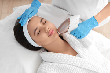 Beautician epilating woman's face in salon, closeup