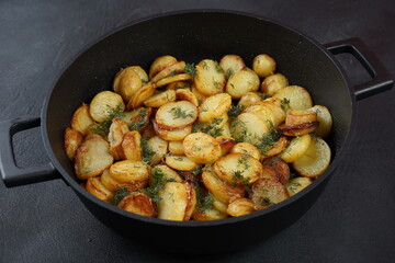 Roasted baby potatoes in iron skillet. Dark grey background.