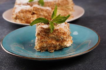 Puff pastry layered cake Napoleon with vanilla cream filling. Piece of classic layer cake Napoleon with mint on plate.