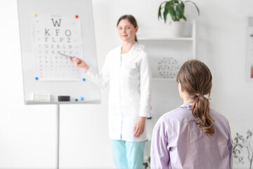 Obraz premium Young woman checking eyesight in clinic, back view