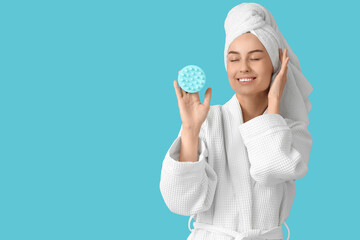 Young happy woman with hair scalp massager on blue background