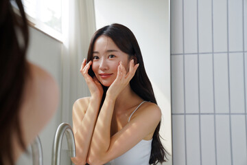 鏡の前でスキンケアをする若いアジア人女性
