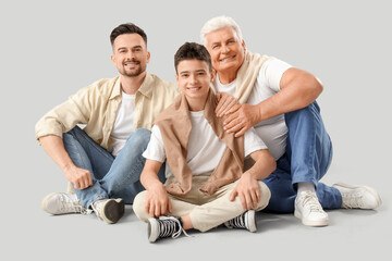 Teenage boy with his dad and grandfather sitting on light background