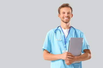 Male medical intern with laptop on light background