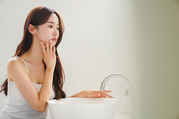 鏡の前でスキンケアをする若いアジア人女性