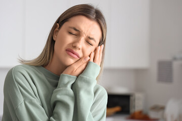 Young woman suffering from tooth ache at home