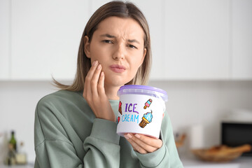 Young woman with ice cream suffering from tooth ache at home