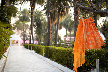 orange indian bridal lehenga hanging from the tree. Indian wedding fashion. wedding concept. modern...