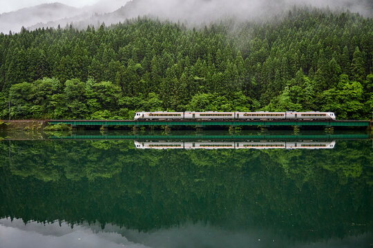 高山本線、霧雨のなかを走る気動車が、飛騨川に映ります