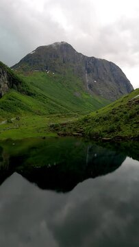  aerial view of a majestic mountain reflected in a tranquil lake, surrounded by lush greenery and towering peaks, creating a breathtaking natural landscape, Norweigan Fjords Stavbergvatnet Urke