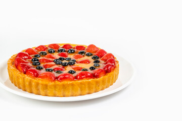 Delicious and appetizing strawberry and blueberry cheesecake on a plate with mango filling on a white background with space for text.