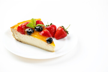 A slice of cheesecake with berries and mango filling on a white plate. A delicious and appetizing dessert.