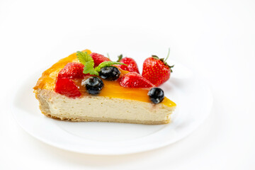 A slice of cheesecake with berries and mango filling on a white plate. A delicious and appetizing dessert.