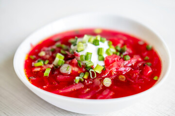 The plate is delicious and appetizing borscht with sour cream and green onions .