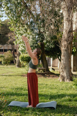 Middle aged woman practicing breathing yoga pranayama outdoors. Yoga instructor doing yoga exercise...