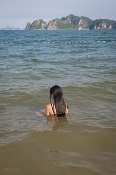 woman relaxing and sitting in the ocean in Vietnam with Ha Long Bay karts mountains in background