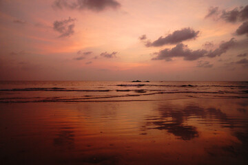 Twilight sky sunset and reflection on the sea water and rocks at Nang Thong Beach at Khao Lak Phang Nga Thailand - Seascape chill vibe on the beach - Orange sky nature abstract background 