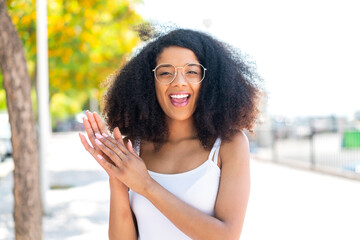 Young African American woman at outdoors With glasses and applauding