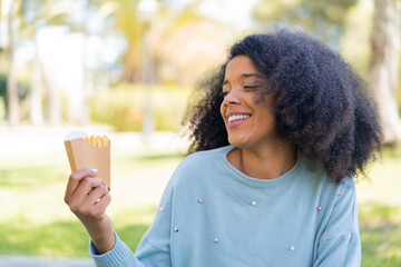 Young African American woman holding fried chips at outdoors with happy expression