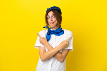 Airplane stewardess woman isolated on yellow background pointing to the laterals having doubts
