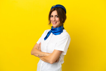 Airplane stewardess woman isolated on yellow background with arms crossed and looking forward