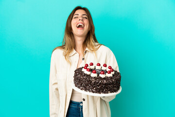Caucasian woman holding birthday cake isolated on blue background laughing