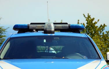 Police car with flashing lights and obscured faces of officers