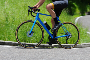 Muscular legs of cyclist during cycling race with blue bicycle on road with great still image