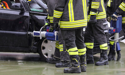 Fototapeta premium firefighter using powerful cordless pneumatic shears to open the jammed door of a crashed car while raining