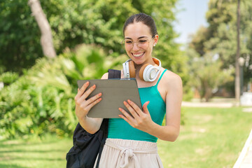 Young pretty woman at outdoors holding a tablet