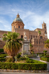 Obraz premium Statue of Santa Rosalia stands before the ornate Palermo Cathedral, nestled among lush greenery under the Sicilian sky, Sicily, Italy