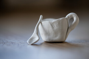 Close-up on a small cups and a spoon made of clay. Homemade clay objects.