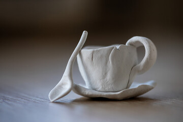 Close-up on a small cups and a spoon made of clay. Homemade clay objects.