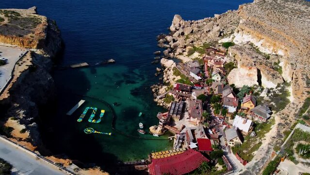 Aerial footage of Popeye Village - builtie set for "Popeye (1980)"ie,  on a sunny summer day. Beautiful drone shot of a theme park village in Malta.