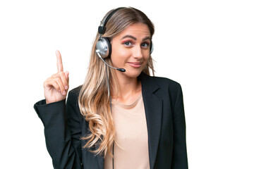 Telemarketer pretty Uruguayan woman working with a headset over isolated background pointing with...