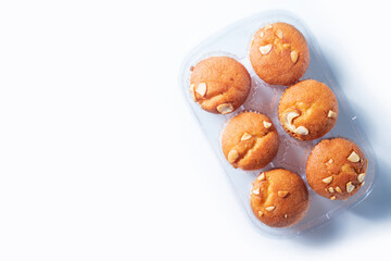 Freshly baked almond muffins in a transparent plastic tray on a white background.