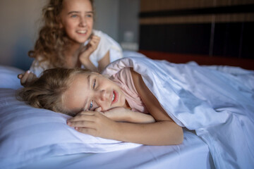 The laughter and joy of two blonde babies playing and fooling around on their big bed after a night...