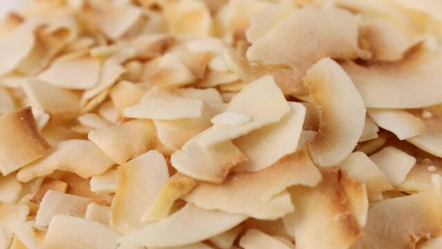 Thin sweet toasted coconut chips falling down close up