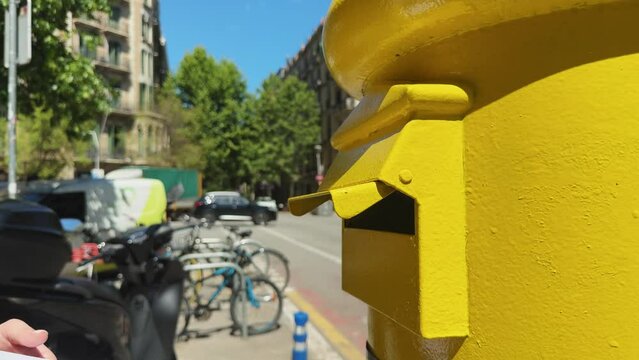 Postbox envelope mail delivery. Woman sending a letter into a yellow letterbox.