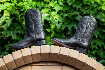 Men cowboy boots stand on stone arch..