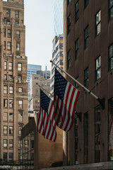 American flags waving in downtown New York City between tall buildings