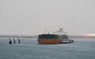 Large Cargo Ship Docked at Port with Wind Turbines in Background on a Foggy Day