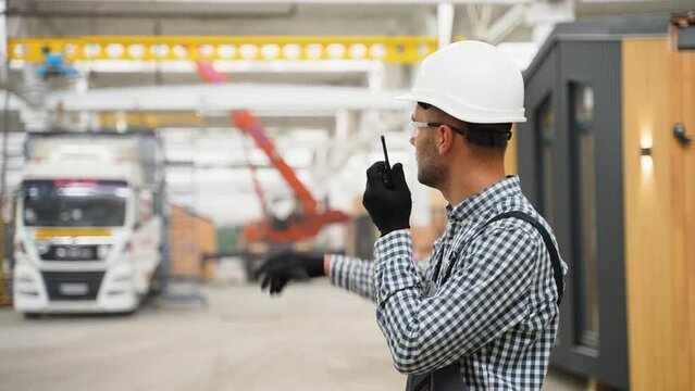 Foreman manages the loading of a prefabricated modular house to truck using walkie talkie
