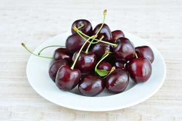a plate of cherries with green stems