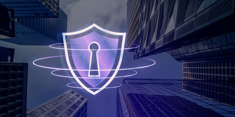 A hologram of a shield with a keyhole displayed between skyscrapers, suggesting digital security concept on an urban background