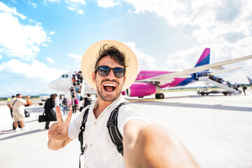 Happy tourist boarding on a plane at the airport - Handsome young man taking selfie in front of airplane - Summertime holidays and transportation life style concept © Davide Angelini